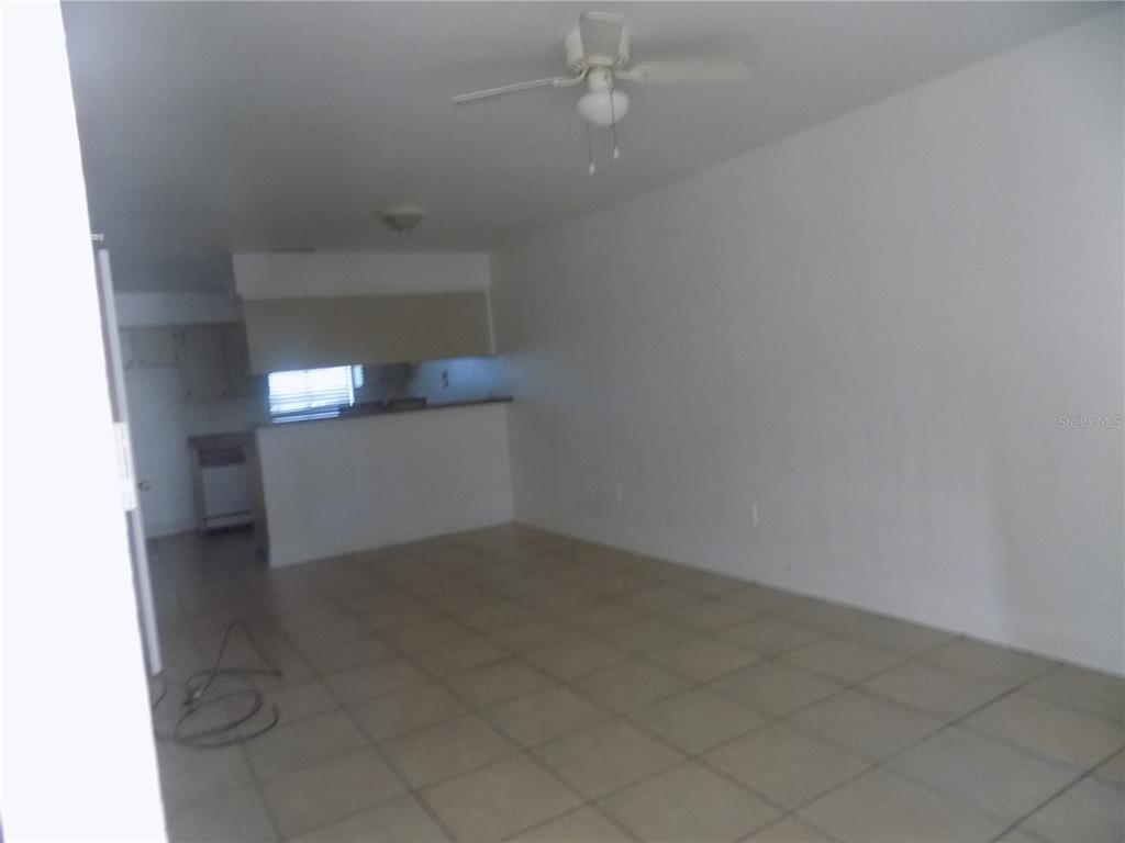An open-concept living area features light-colored floor tiles, white walls, and a ceiling fan — 713 SW 69 STREET, GAINESVILLE, FL