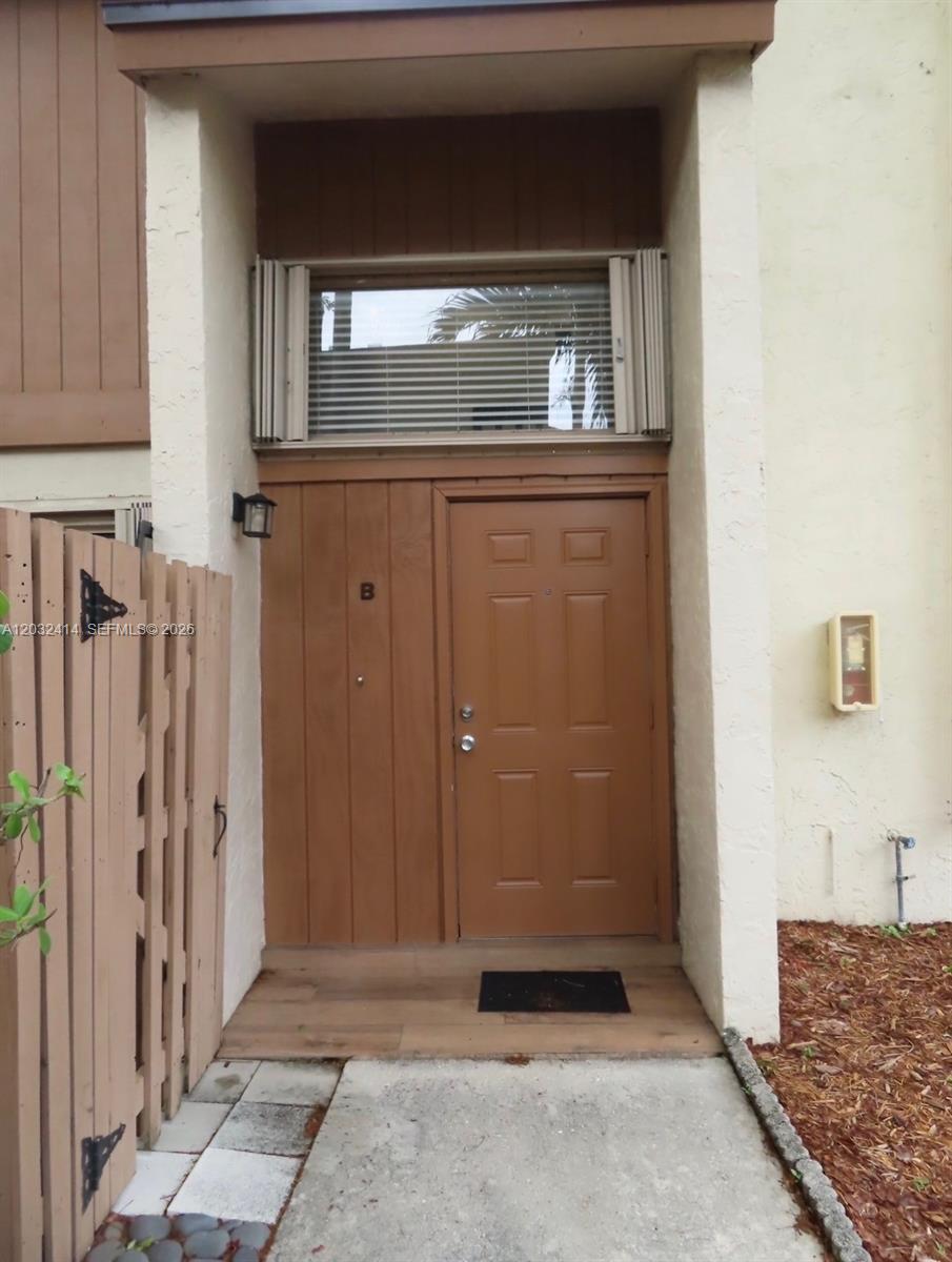 The exterior entrance features a brown door, a transom window, and a wooden fence — 11543 SW 109th Rd # 24B, Miami FL 33176, MIAMI, FL
