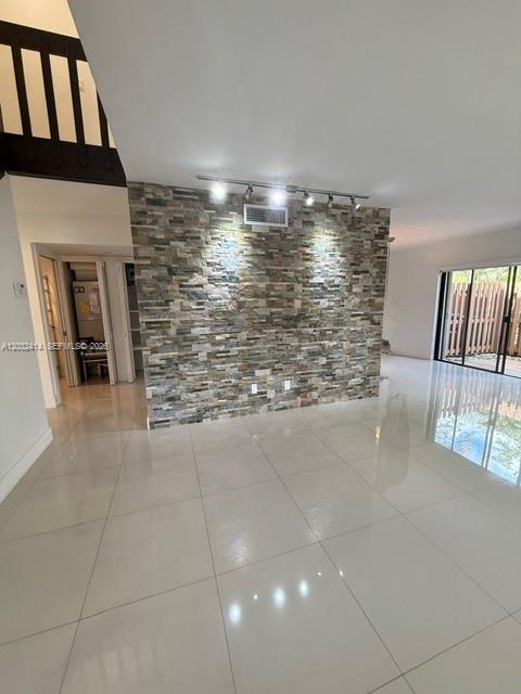 A room with large white floor tiles and a prominent stone-clad accent wall — 11543 SW 109th Rd # 24B, Miami FL 33176, MIAMI, FL