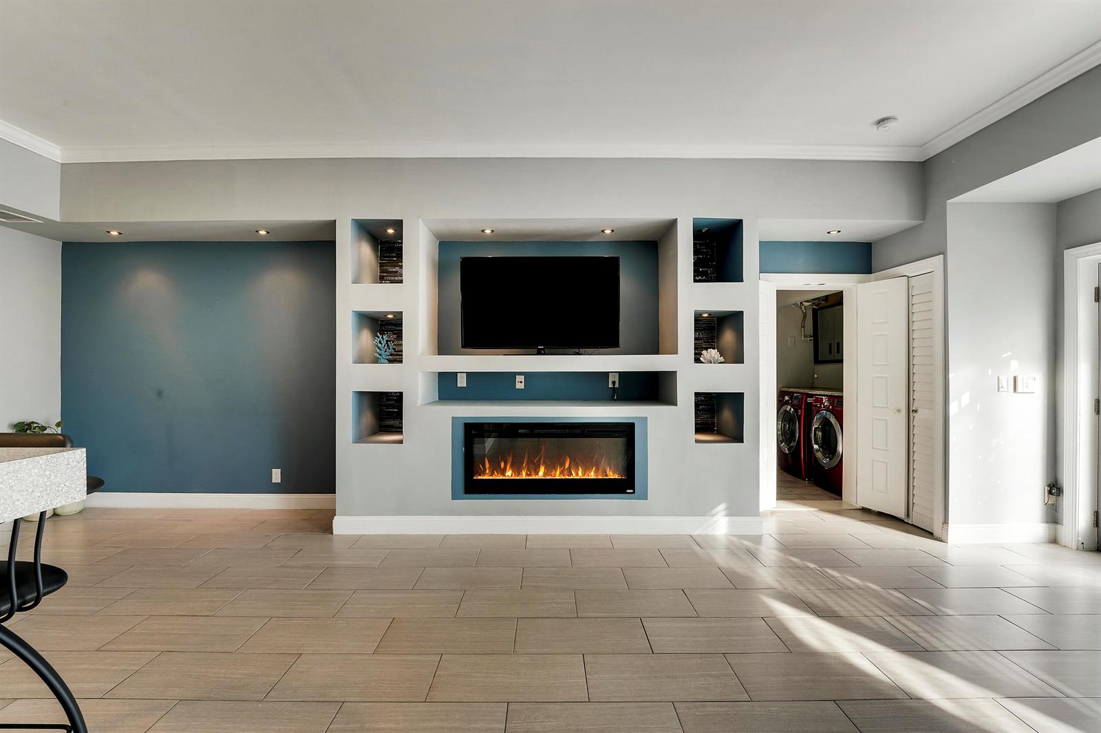 A living room features a built-in media wall with a fireplace, television, and shelving — 1827 Len Drive, North Palm Beach FL 33408, NORTH PALM BEACH, FL