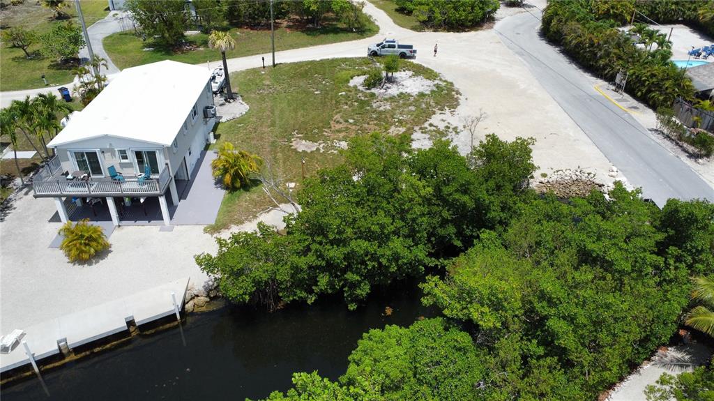 An aerial view shows a stilt house with a deck next to a canal and road — 2080 CORAL WAY, BIG PINE KEY, FL