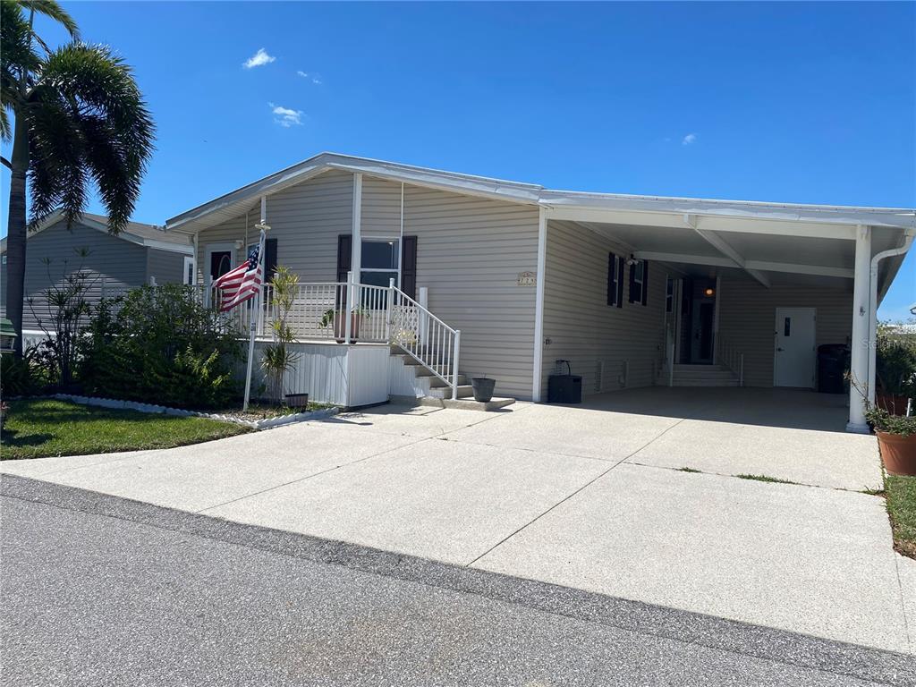 A single-story manufactured home with light siding, a front porch, and an attached carport — 724 BLACKBURN BOULEVARD, NORTH PORT, FL