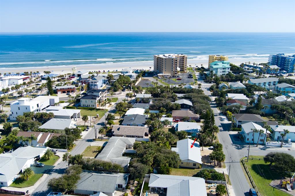 An aerial view shows a coastal neighborhood with a red arrow pointing to a house — 712-714 OAKWOOD AVENUE, NEW SMYRNA BEACH, FL