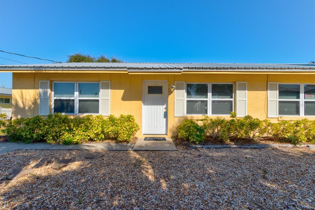 A yellow single-story house exterior features a white front door, shutters, and a gravel yard — 712-714 OAKWOOD AVENUE, NEW SMYRNA BEACH, FL