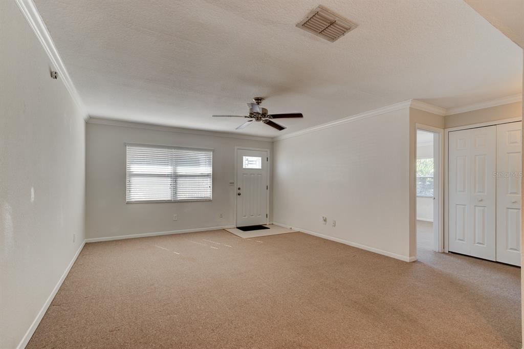 A carpeted living room features a ceiling fan, a front door, and a closet — 712-714 OAKWOOD AVENUE, NEW SMYRNA BEACH, FL