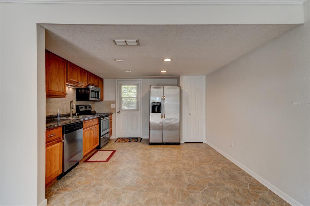 A kitchen features wood cabinets, stainless steel appliances, and light-colored tile flooring — 712-714 OAKWOOD AVENUE, NEW SMYRNA BEACH, FL