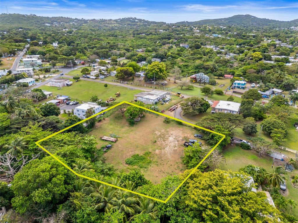 An aerial view shows a vacant, grassy lot outlined in yellow within a residential area — Bo Florida SOLAR 4, VIEQUES, PR