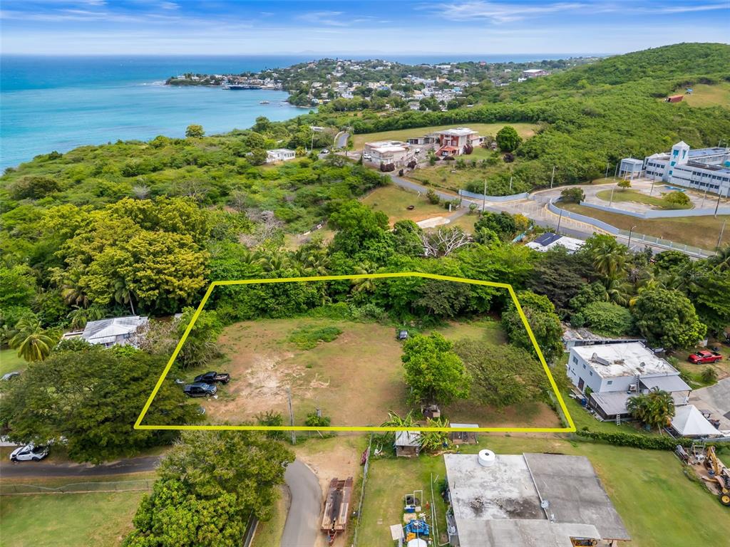 An aerial view shows a vacant, rectangular lot outlined in yellow near a coastal town — Bo Florida SOLAR 4, VIEQUES, PR