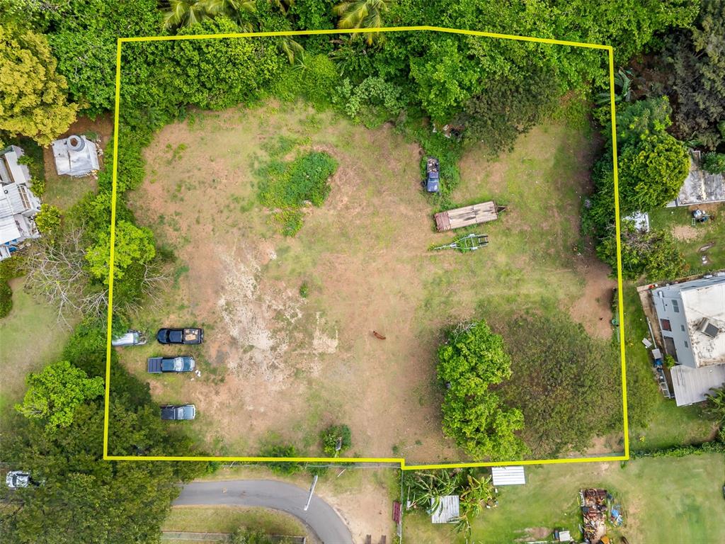 An aerial view shows a large, grassy, rectangular lot outlined in yellow with several vehicles parked — Bo Florida SOLAR 4, VIEQUES, PR