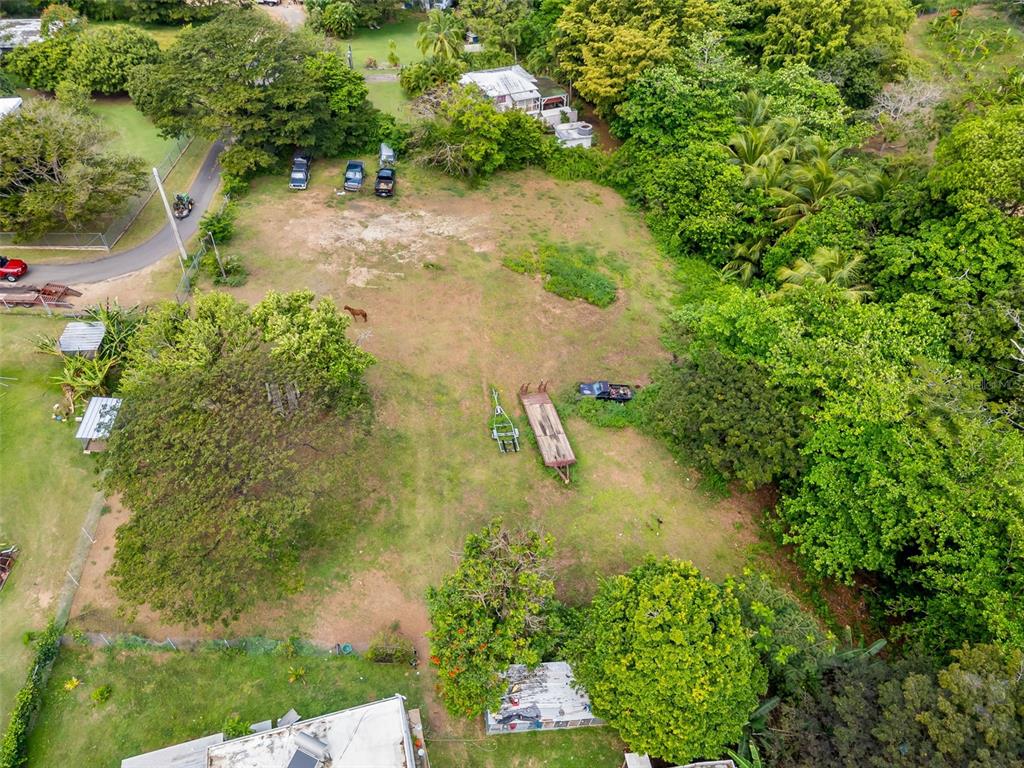 An aerial view shows a grassy lot with several parked vehicles and scattered trees — Bo Florida SOLAR 4, VIEQUES, PR