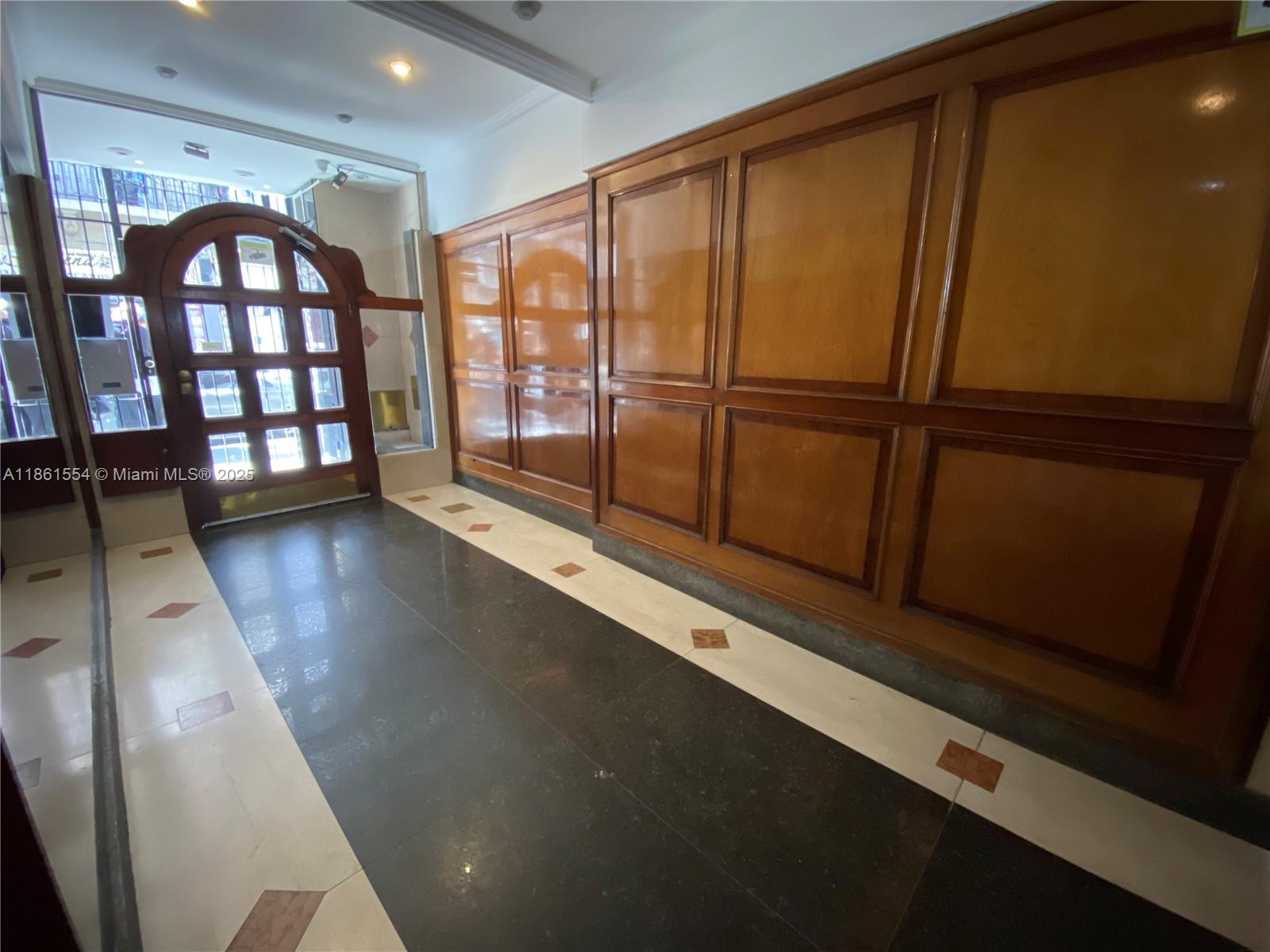 An interior building lobby features dark tile flooring, light stone borders, and wood-paneled walls — Riobamba 72 Buenos Aires Riobamba 72 Buenos Aires # 8, FL 72, FL