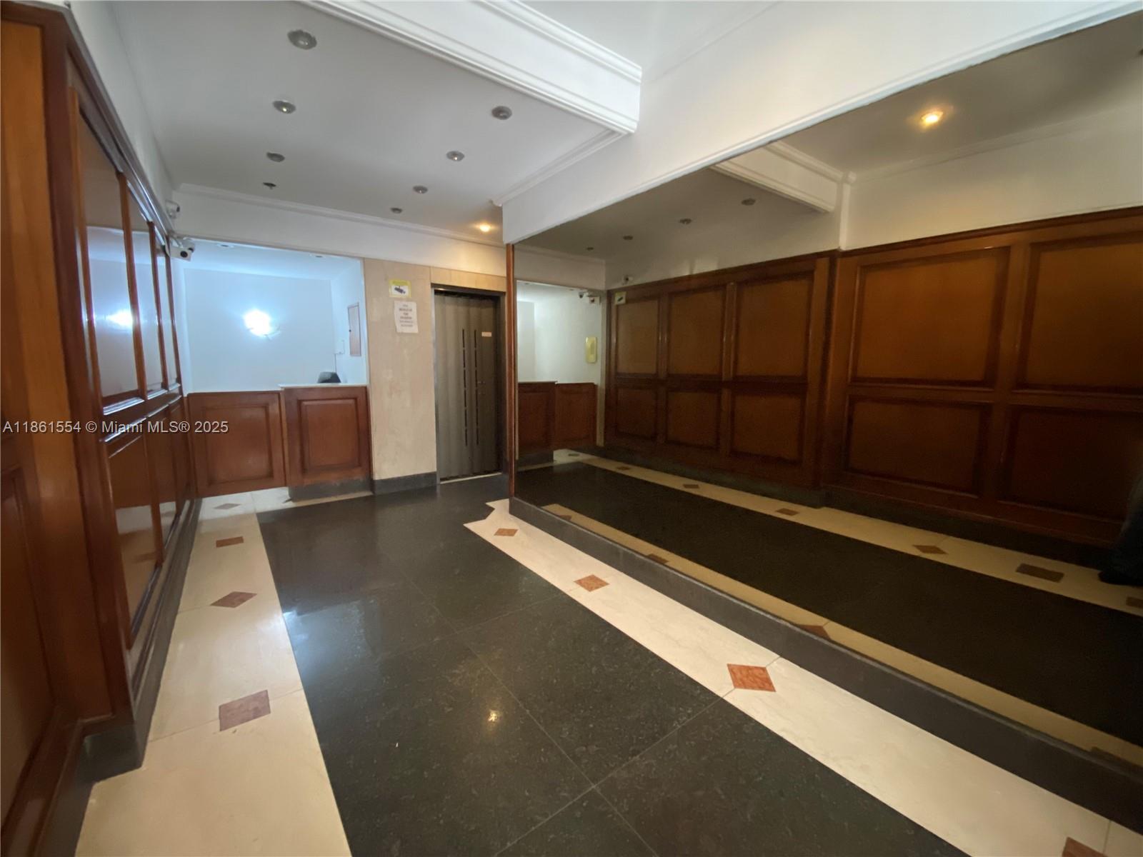 A lobby features dark tile flooring, wood-paneled walls, a mirror, and an elevator — Riobamba 72 Buenos Aires Riobamba 72 Buenos Aires # 8, FL 72, FL