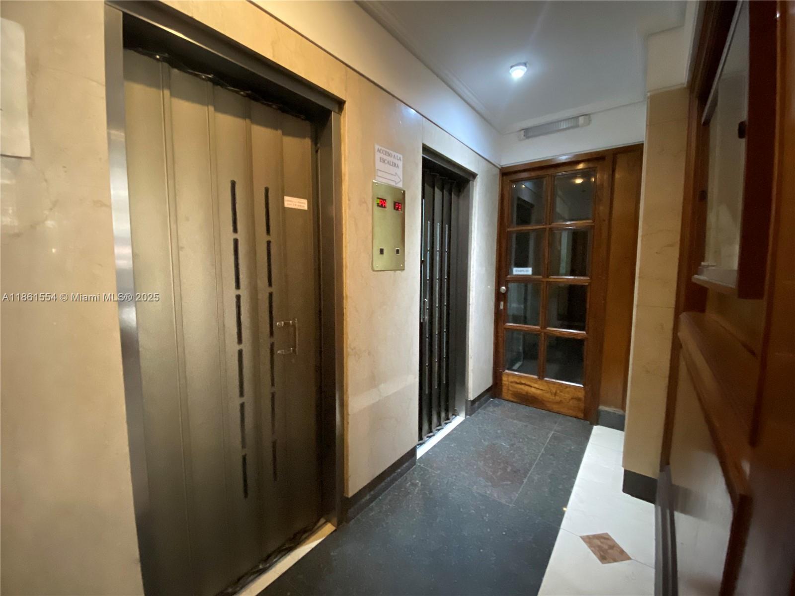A hallway features two elevator doors, a wooden glass door, and marble-style wall paneling — Riobamba 72 Buenos Aires Riobamba 72 Buenos Aires # 8, FL 72, FL