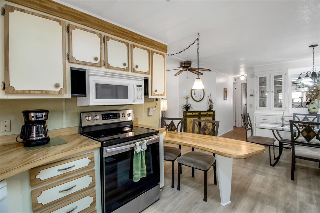 A kitchen features wood-trimmed white cabinets, a stainless steel stove, and an attached dining table — 5619 BAYSHORE ROAD UNIT 160, PALMETTO, FL