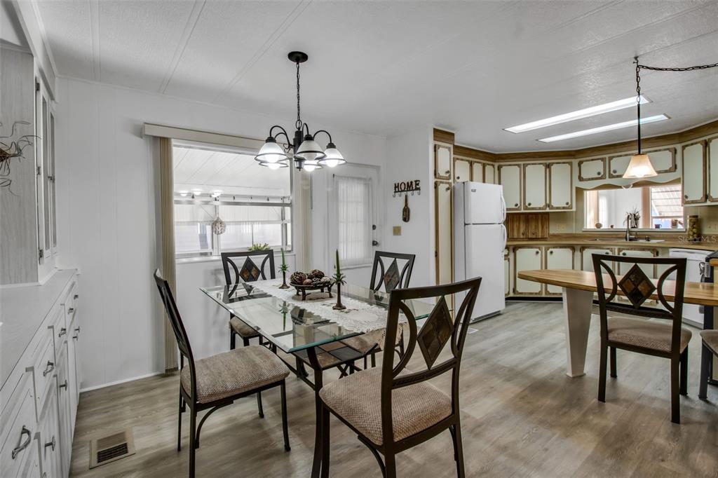 A dining area with a glass table and chairs adjacent to a kitchen with white cabinets — 5619 BAYSHORE ROAD UNIT 160, PALMETTO, FL