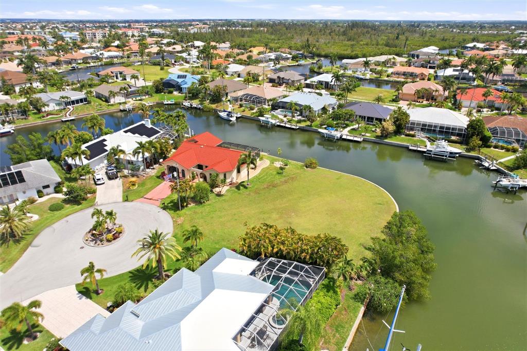 An aerial view shows a waterfront neighborhood with houses, swimming pools, and docked boats — 1501 ORIOLE COURT, PUNTA GORDA, FL
