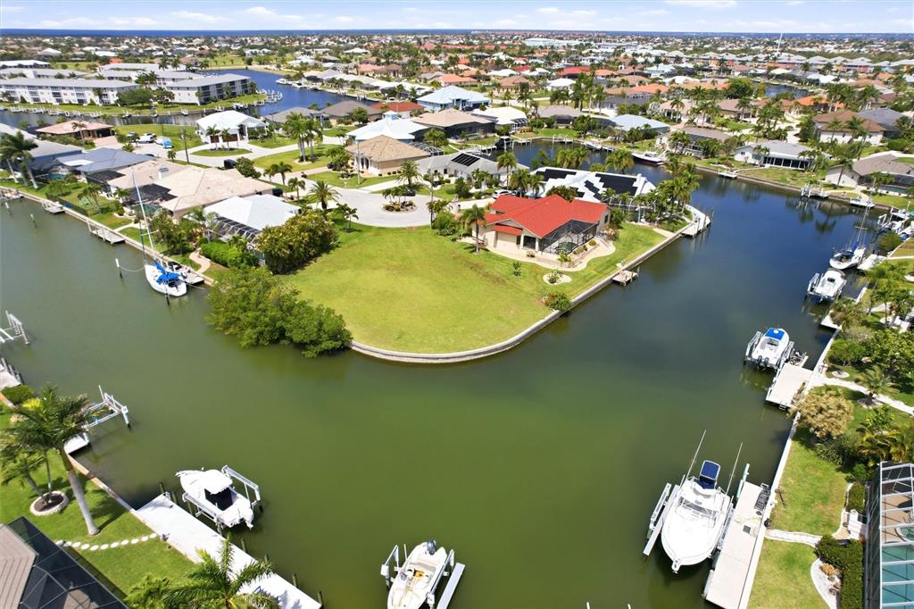 An aerial view shows a waterfront house with a red roof on a canal lot — 1501 ORIOLE COURT, PUNTA GORDA, FL