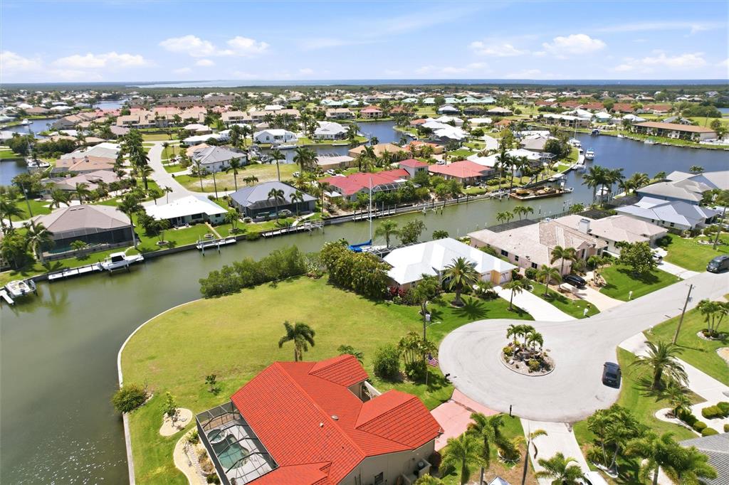 An aerial view shows waterfront homes with tiled roofs, boat docks, and a cul-de-sac — 1501 ORIOLE COURT, PUNTA GORDA, FL