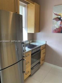 A stainless steel refrigerator stands next to a kitchen stove and light wood cabinets — 2421 Lake Pancoast Dr # 3B, Miami Beach FL 33140, MIAMI BEACH, FL