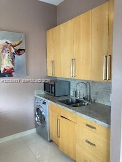 A laundry room features light wood cabinets, a stainless steel microwave, and a front-loading washer — 2421 Lake Pancoast Dr # 3B, Miami Beach FL 33140, MIAMI BEACH, FL