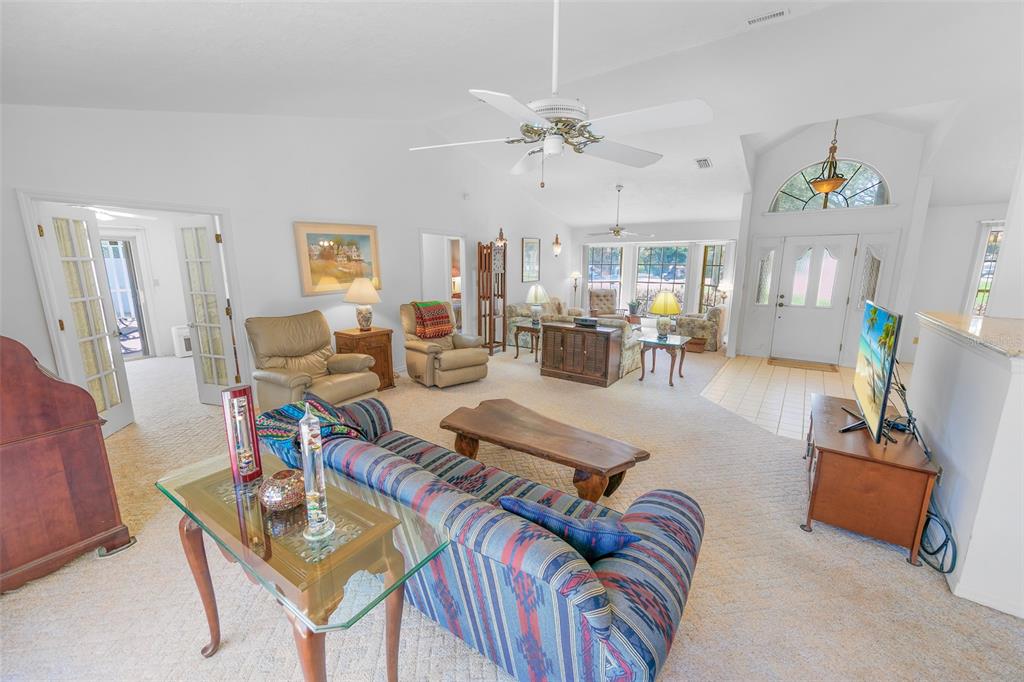 A spacious living room features a patterned sofa, beige armchairs, and a vaulted ceiling — 4801 S PENINSULA DRIVE, PONCE INLET, FL