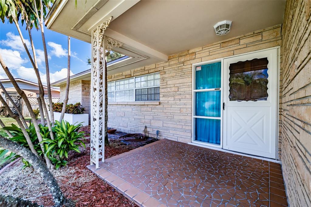 A covered front porch with stone walls, a tiled floor, and a decorative metal support column — 5004 S HESPERIDES STREET, TAMPA, FL