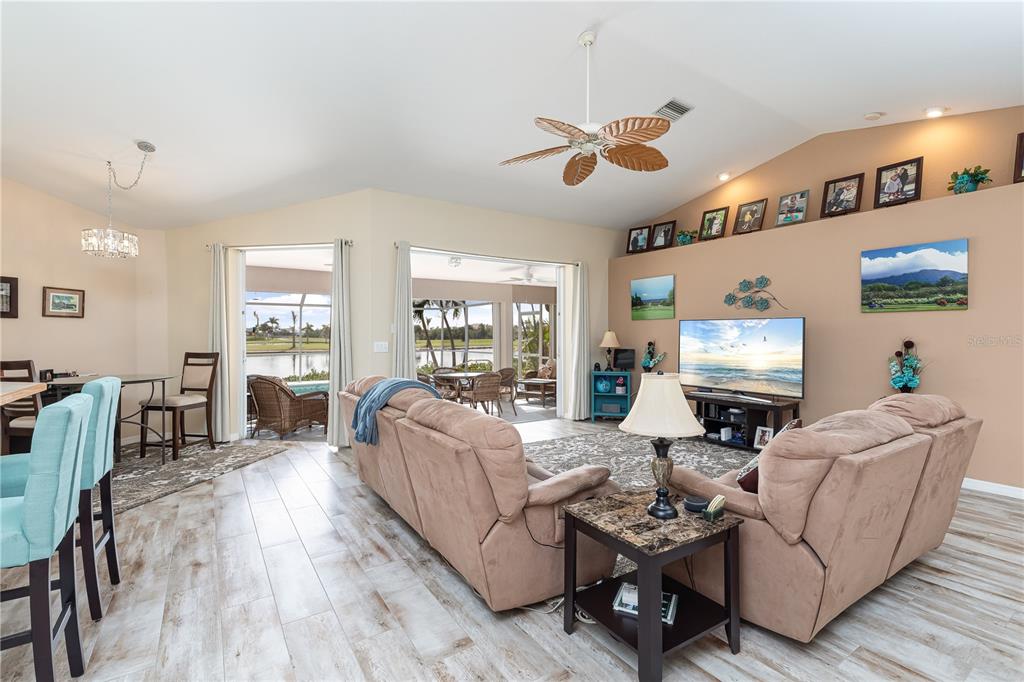 A living room with light tile floors, tan walls, a ceiling fan, and sliding glass doors — 4077 LA COSTA ISLAND COURT, PUNTA GORDA, FL