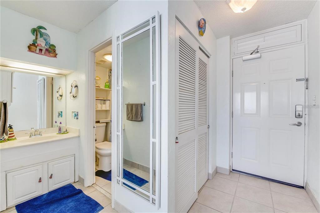 A bathroom vanity and toilet area next to a closet and an entryway door — 3501 S ATLANTIC AVENUE UNIT 5200, DAYTONA BEACH, FL