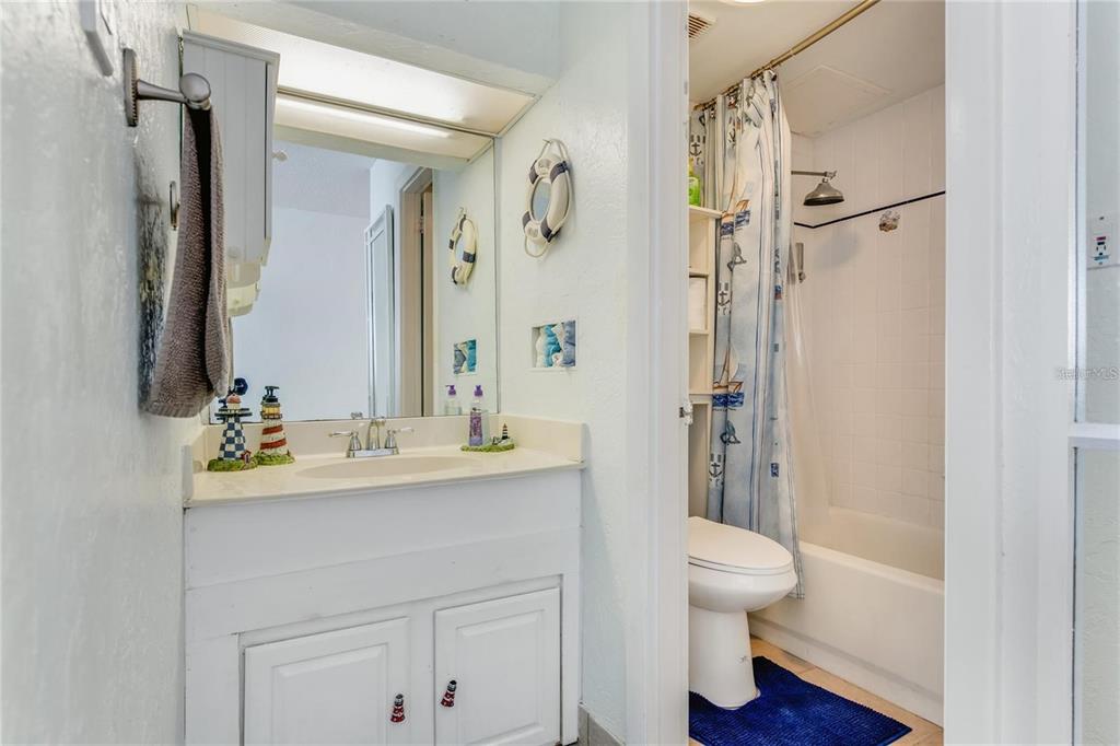 A bathroom features a white vanity, a mirror, and a shower-tub combination with a curtain — 3501 S ATLANTIC AVENUE UNIT 5200, DAYTONA BEACH, FL