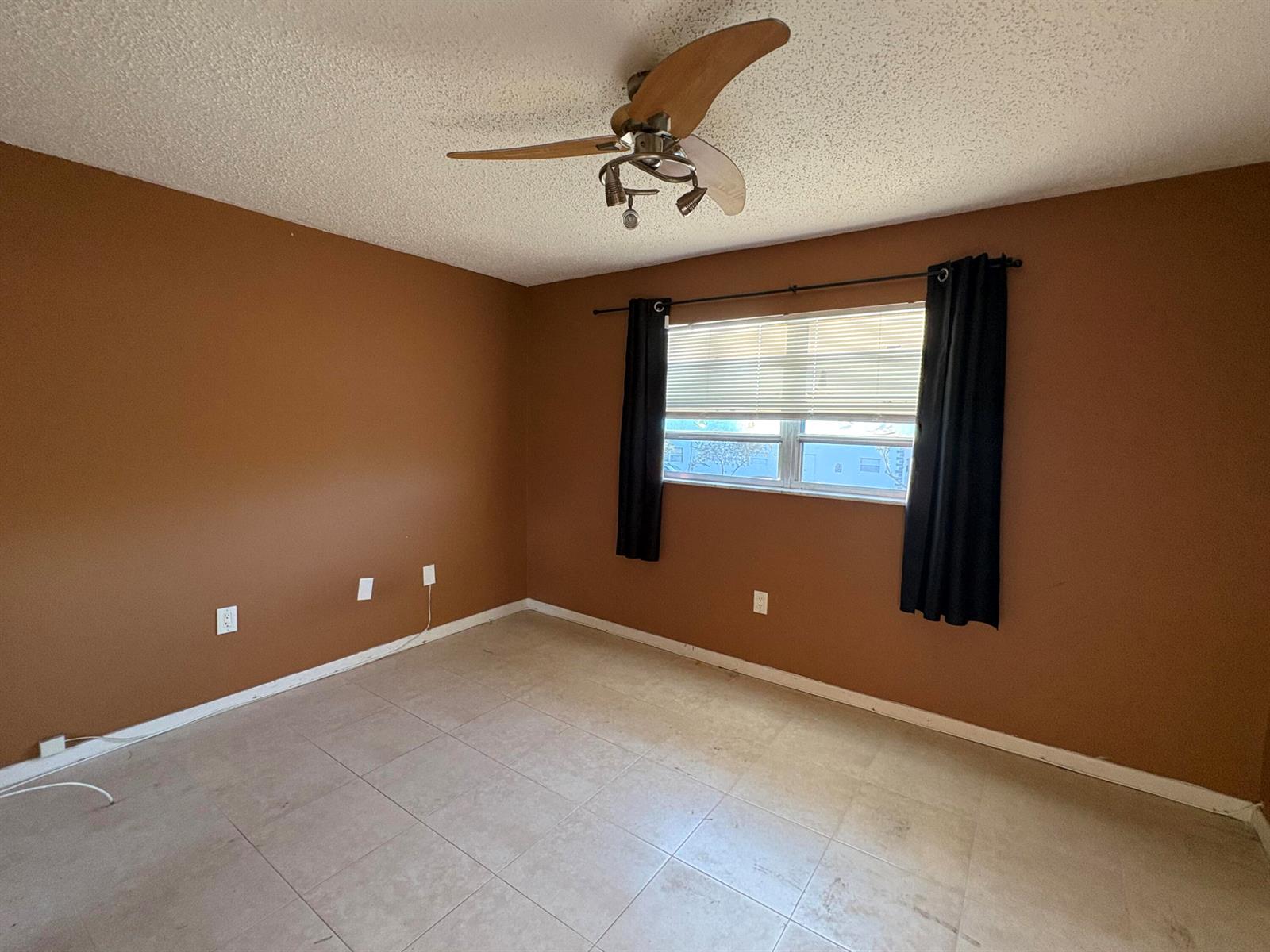 An empty room with brown walls, tile flooring, a ceiling fan, and a window — 650 SW 2nd Avenue # 2460, Boca Raton FL 33432, BOCA RATON, FL