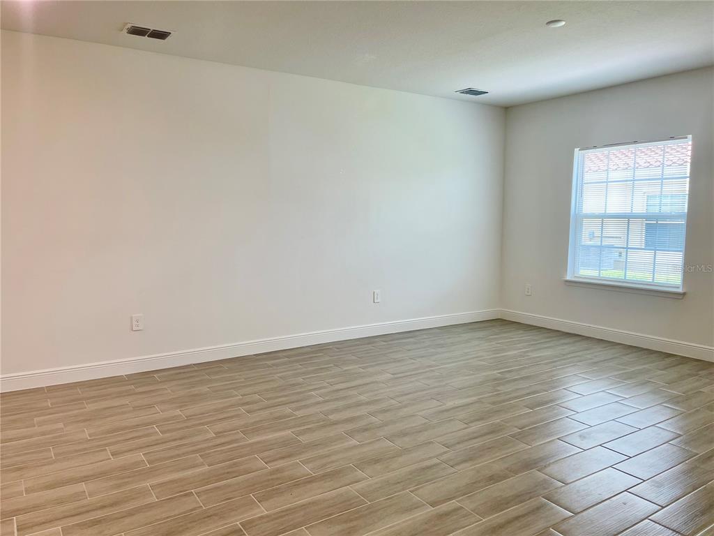 An empty room with light-colored walls, wood-look tile flooring, and a single window — 1732 PACIFIC ROAD, POINCIANA, FL