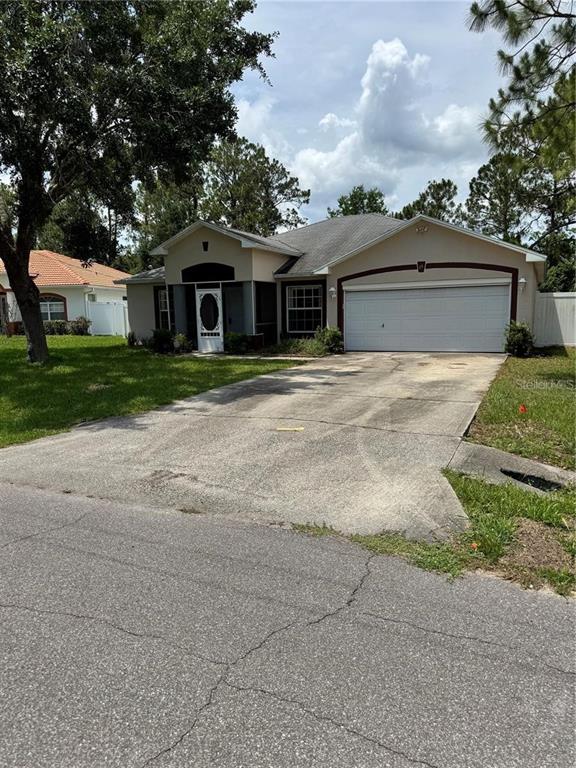 A single-story house with a two-car garage, a concrete driveway, and a screened front entryway — 15 PRATTWOOD LANE, PALM COAST, FL