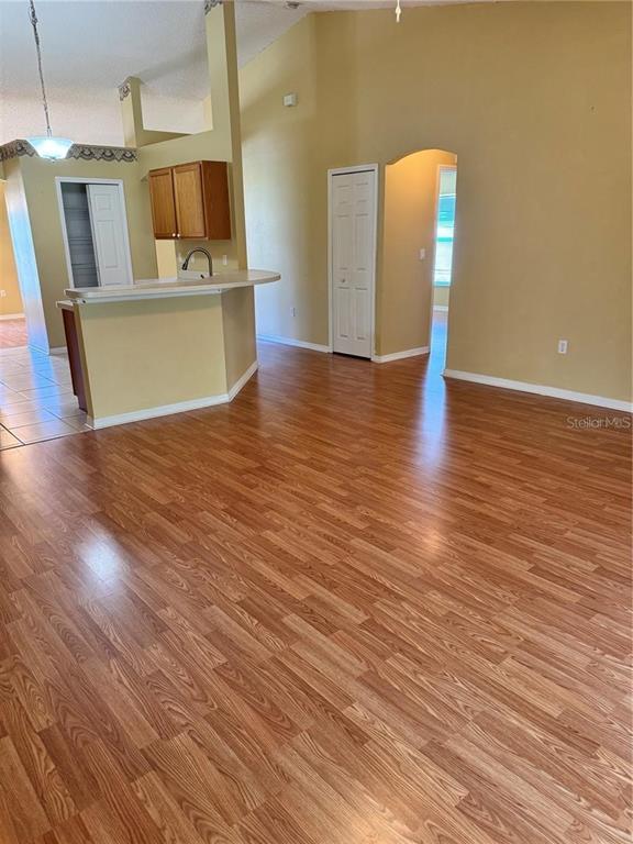 A living area with wood-look flooring, a kitchen breakfast bar, and beige walls — 15 PRATTWOOD LANE, PALM COAST, FL