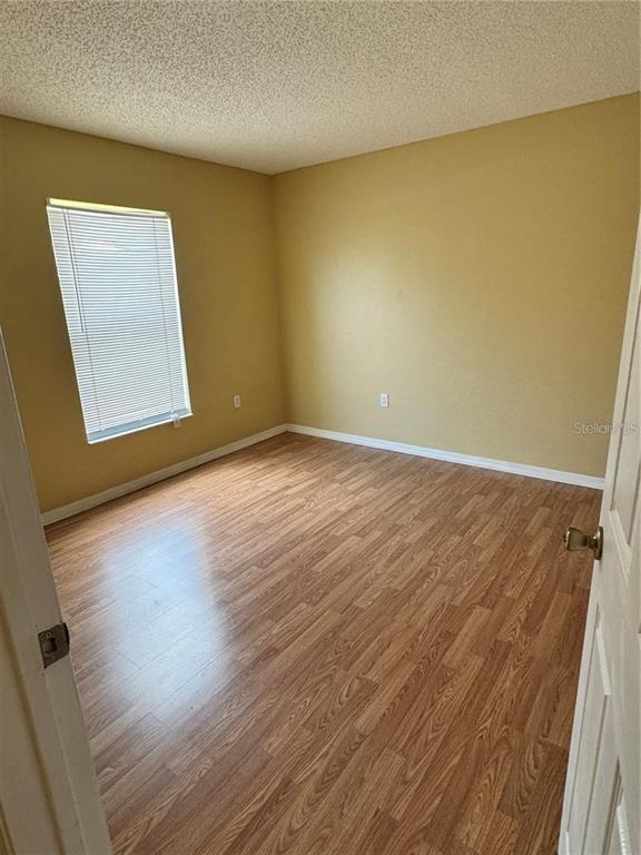 An empty bedroom features light-colored walls, wood-look laminate flooring, and a window with blinds — 15 PRATTWOOD LANE, PALM COAST, FL
