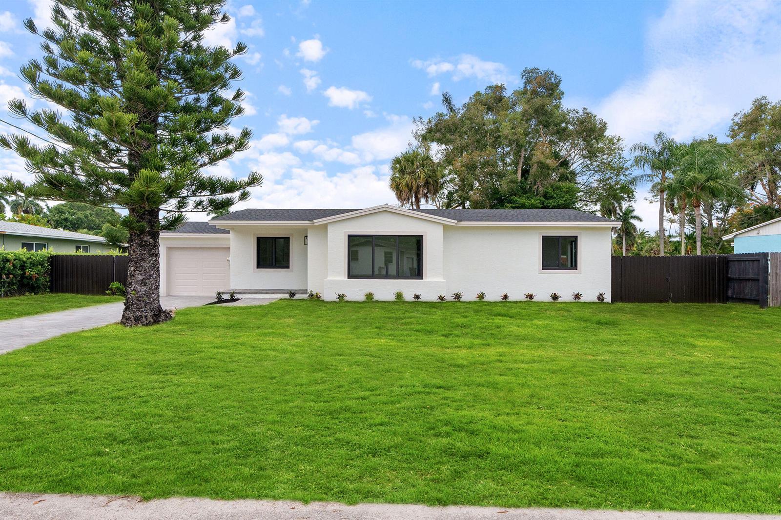 A white, single-story house with a dark roof, garage, and large front lawn — 3185 Riddle Road, West Palm Beach FL 33406, WEST PALM BEACH, FL