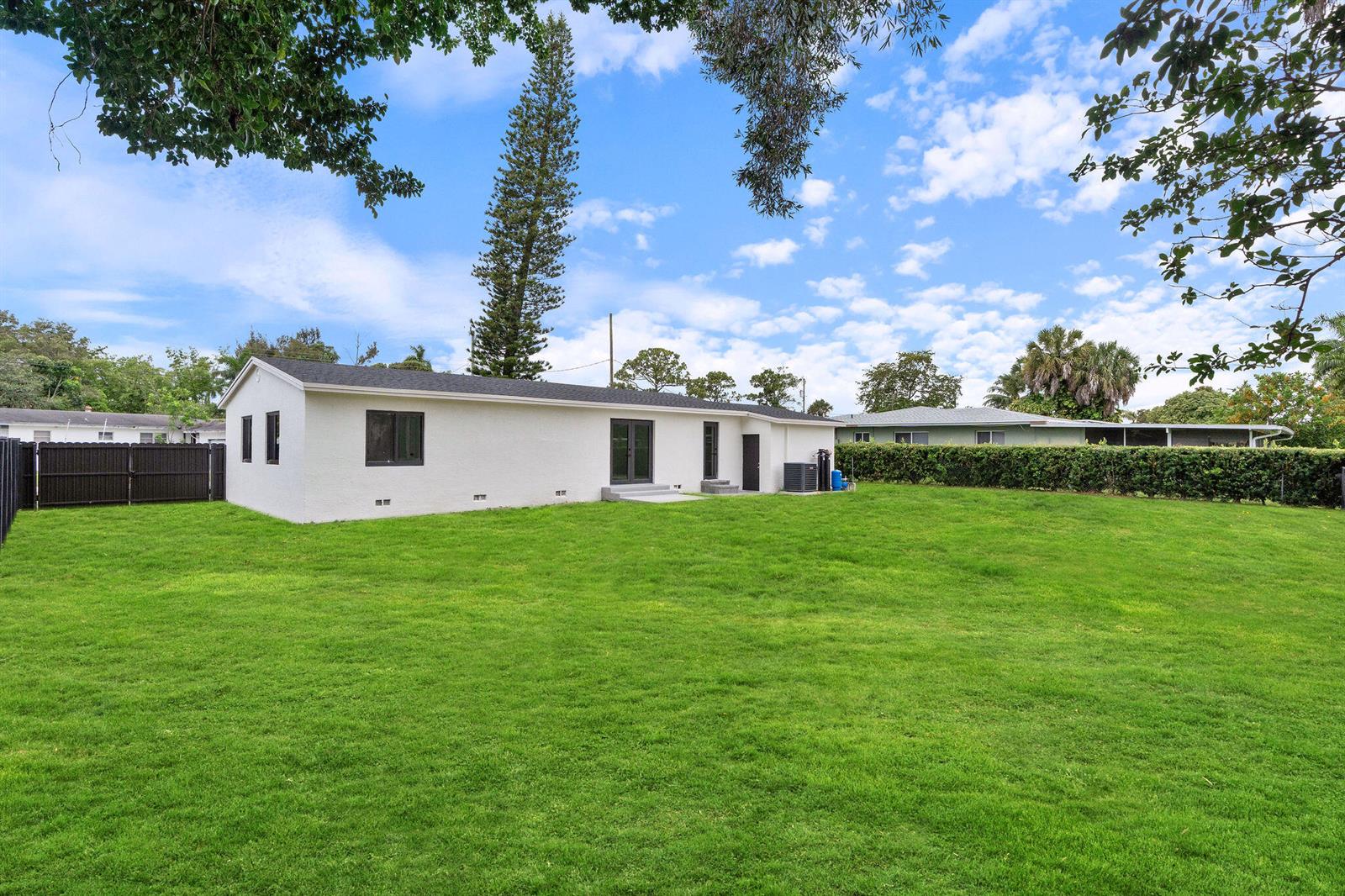 The exterior of a white, single-story house with a large green lawn and fence — 3185 Riddle Road, West Palm Beach FL 33406, WEST PALM BEACH, FL