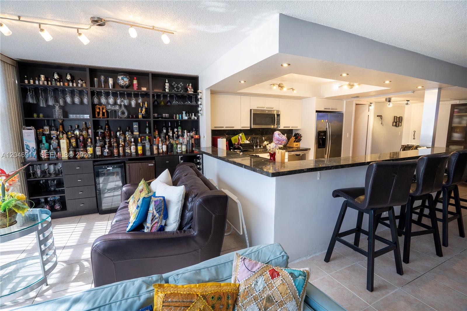 A living room features a built-in bar, a leather sofa, and a kitchen breakfast bar — 601 Three Islands Blvd # 117, Hallandale Beach FL 33009, HALLANDALE BEACH, FL