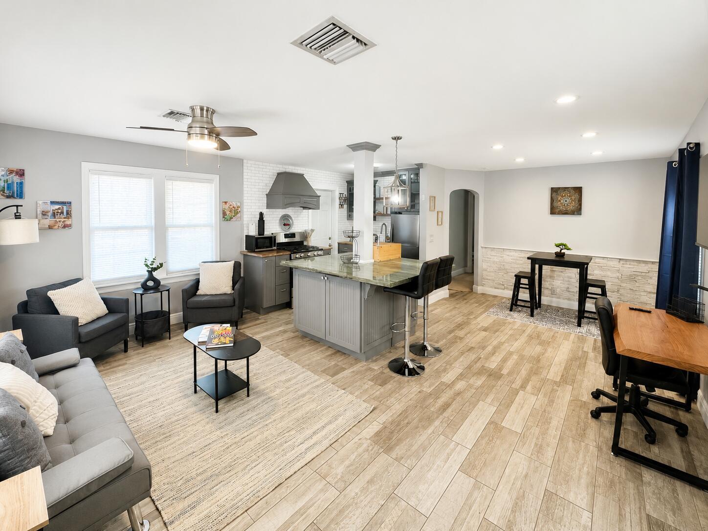 An open-concept living area features a kitchen island, gray cabinetry, and light wood-look flooring — 322 S L Street, FL 33460, FL
