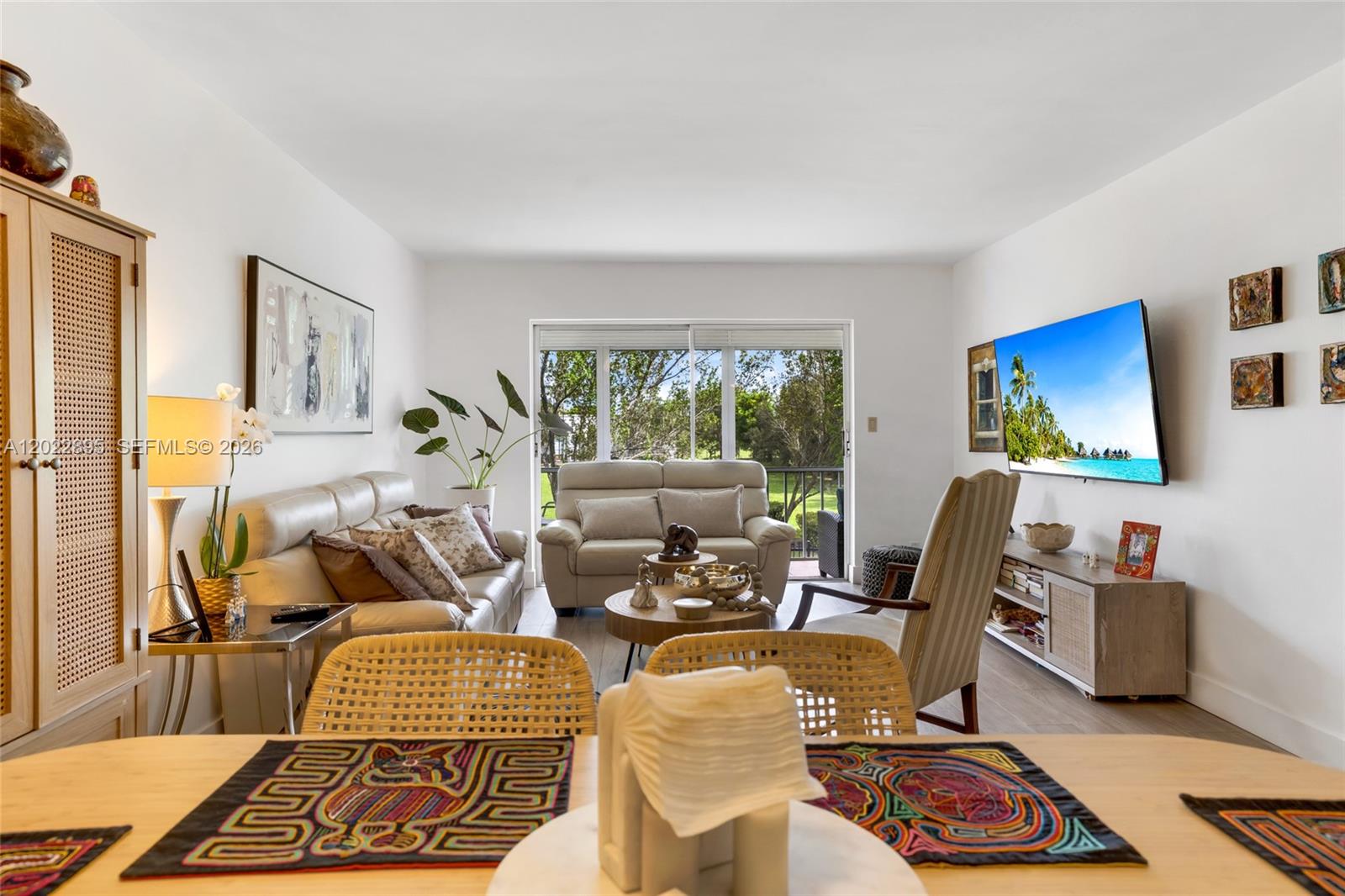 A living room features a beige sofa, a striped armchair, and a television mounted on white walls — 950 Hillcrest Dr # 212, Hollywood FL 33021, HOLLYWOOD, FL