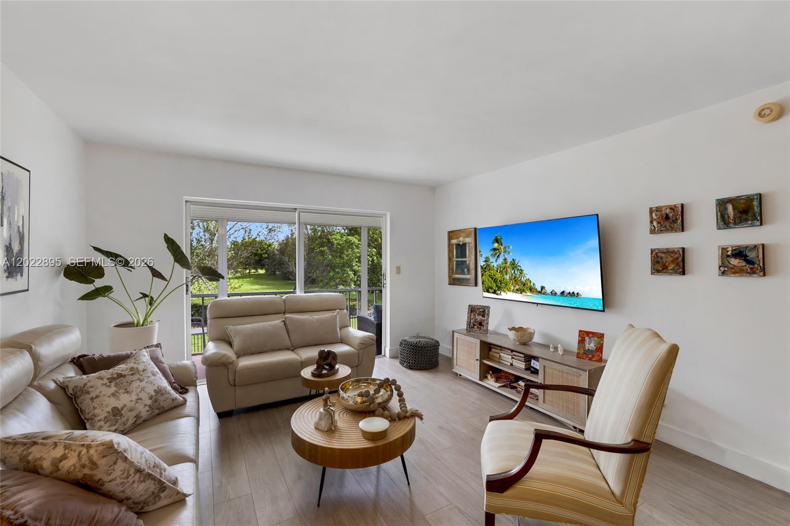 A living room features light-colored furniture, a wall-mounted television, and a sliding glass door — 950 Hillcrest Dr # 212, Hollywood FL 33021, HOLLYWOOD, FL