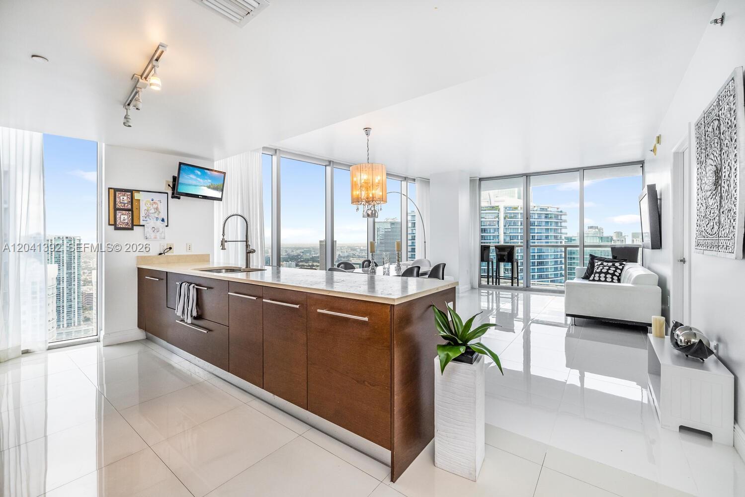 A modern kitchen with a wooden island and white tile floors overlooks a city skyline — 475 BRICKELL AVE # 4715, Miami FL 33131, MIAMI, FL