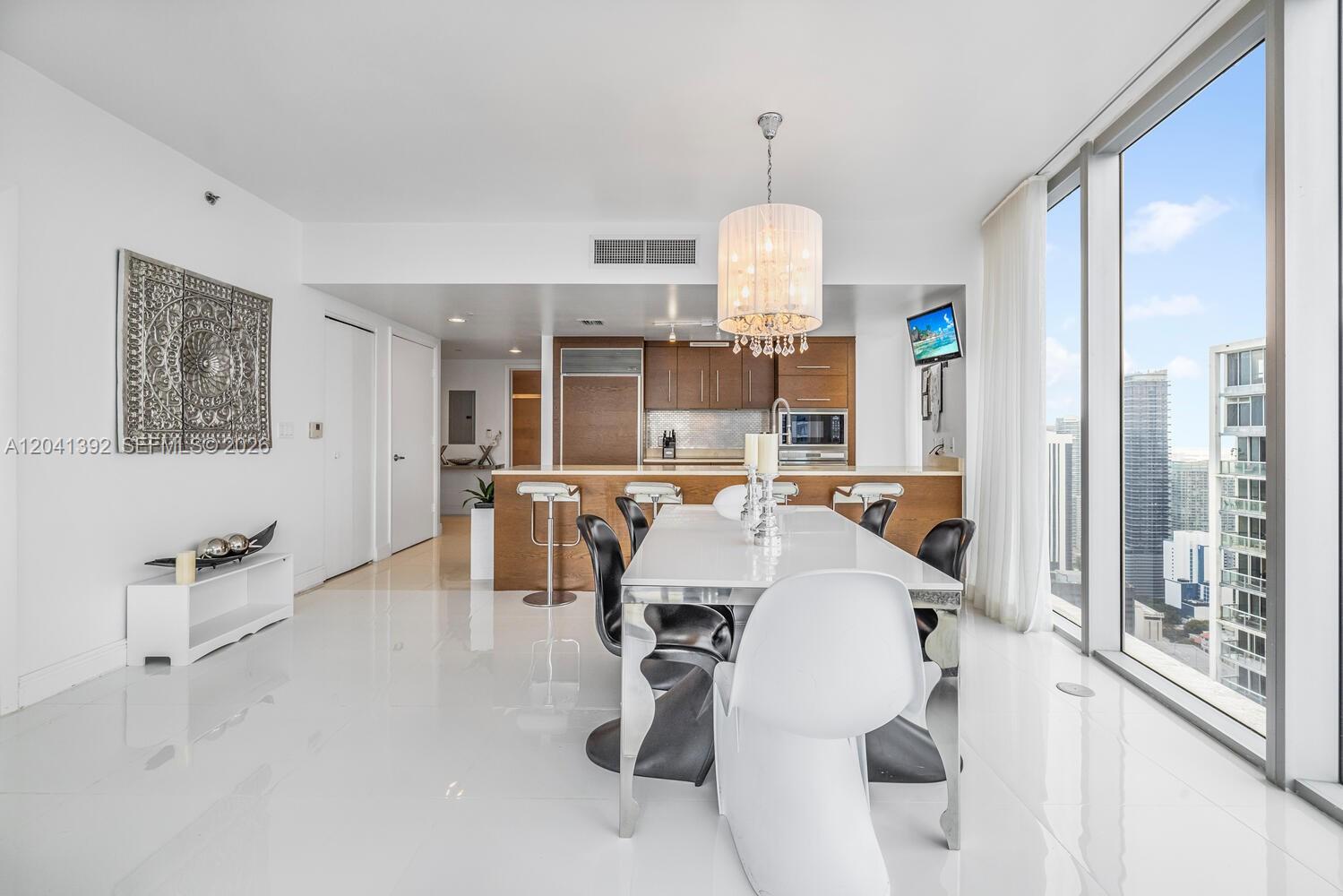 A modern dining area features a white table, black chairs, and floor-to-ceiling windows — 475 BRICKELL AVE # 4715, Miami FL 33131, MIAMI, FL