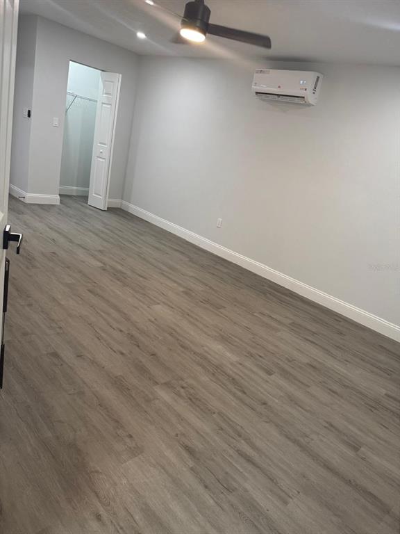A bedroom features light gray walls, wood-look flooring, a ceiling fan, and a wall-mounted air conditioner — 1905 ROSLYN AVENUE, BRADENTON, FL