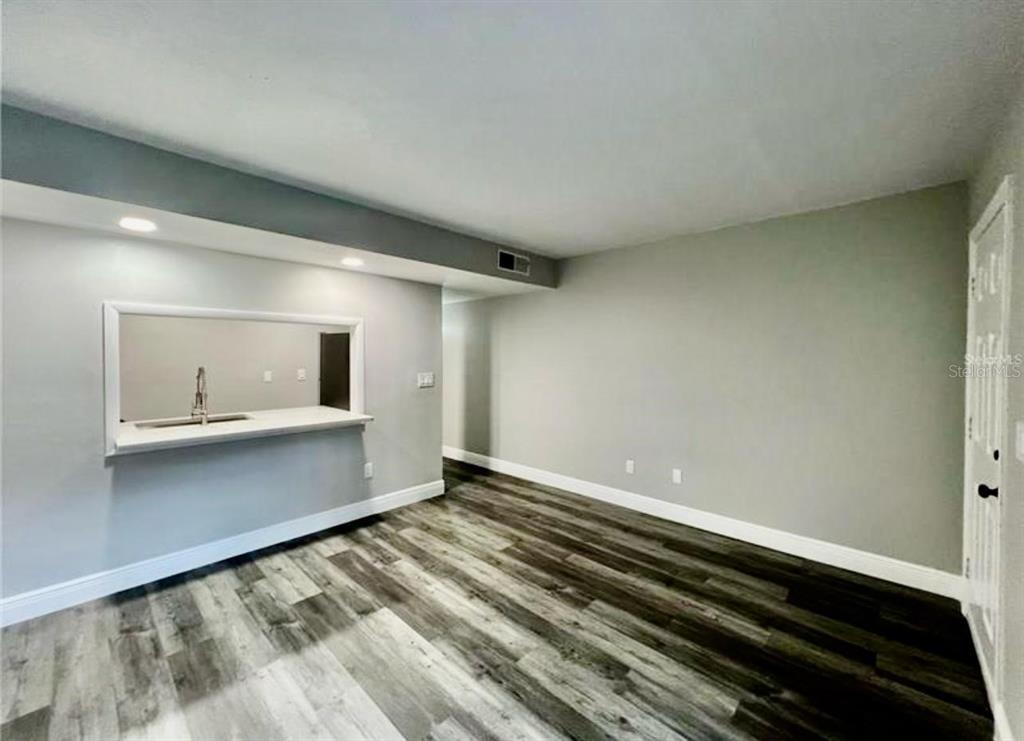 A room with gray walls, wood-look flooring, and a kitchen pass-through window — 7108 WATERSIDE DRIVE UNIT 103, TAMPA, FL