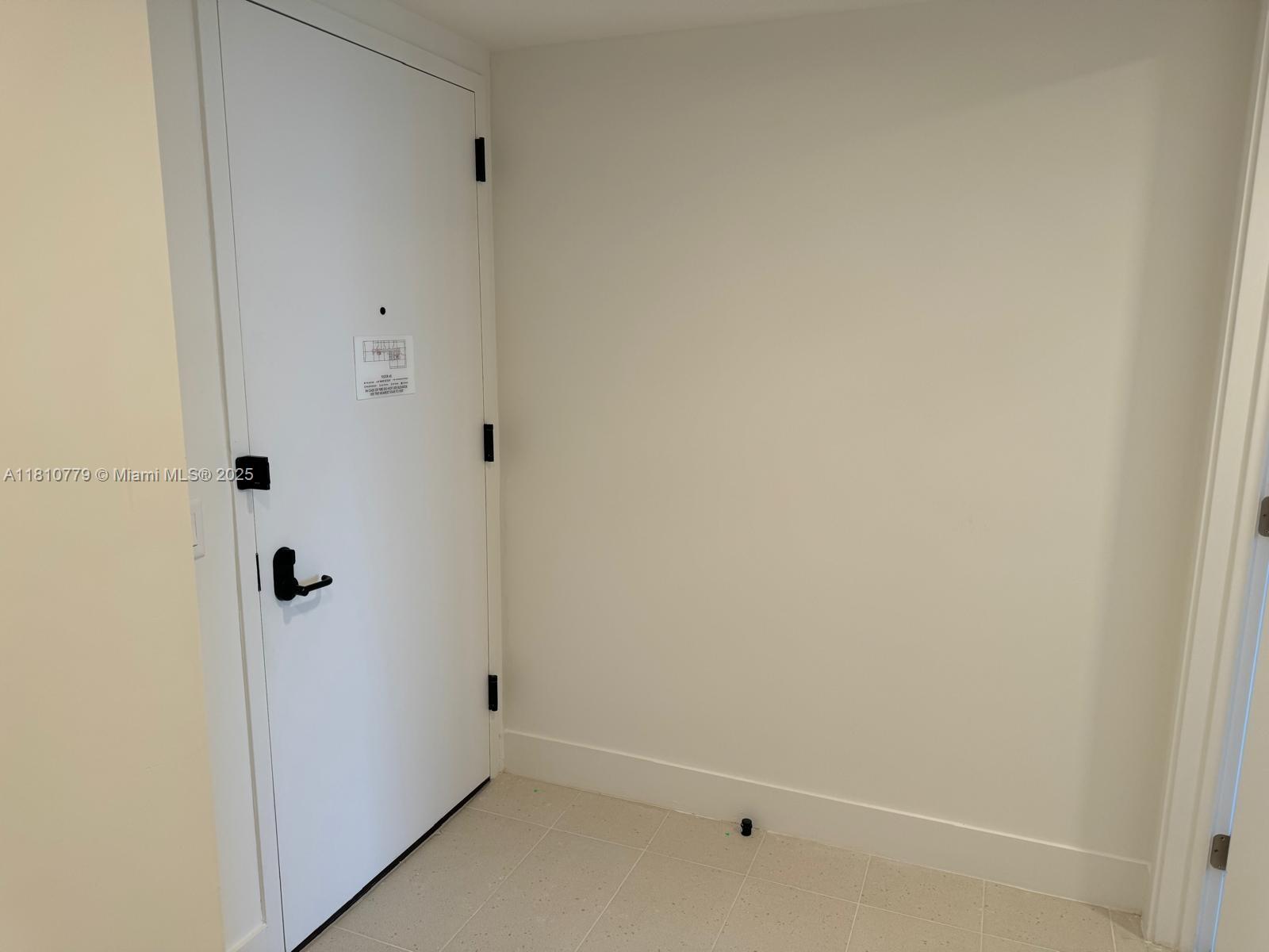 A white door with black hardware is set against a plain wall with tiled flooring — 159 NE 6TH ST # 4215, Miami FL 33132, MIAMI, FL