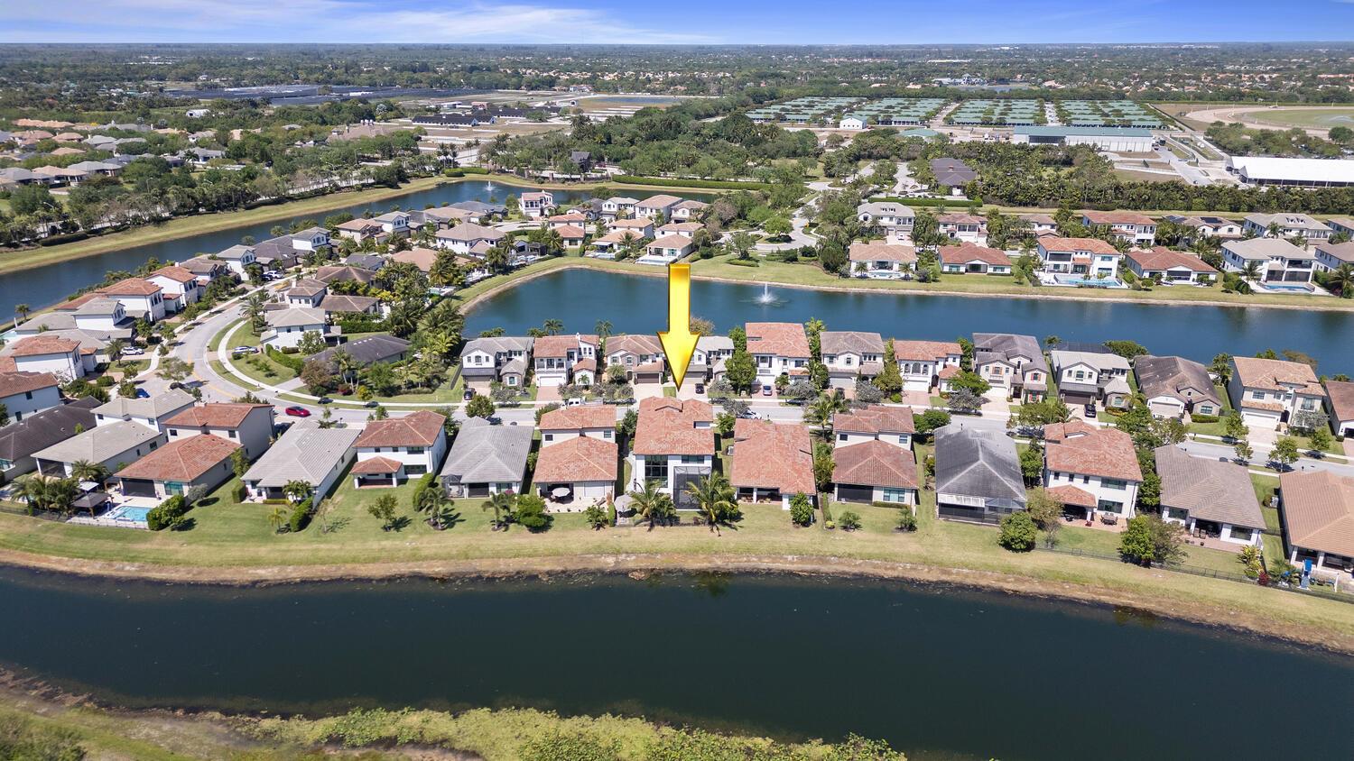 An aerial view shows a residential neighborhood with houses surrounding a central lake — 8451 Grand Prix Lane, Boynton Beach FL 33472, BOYNTON BEACH, FL