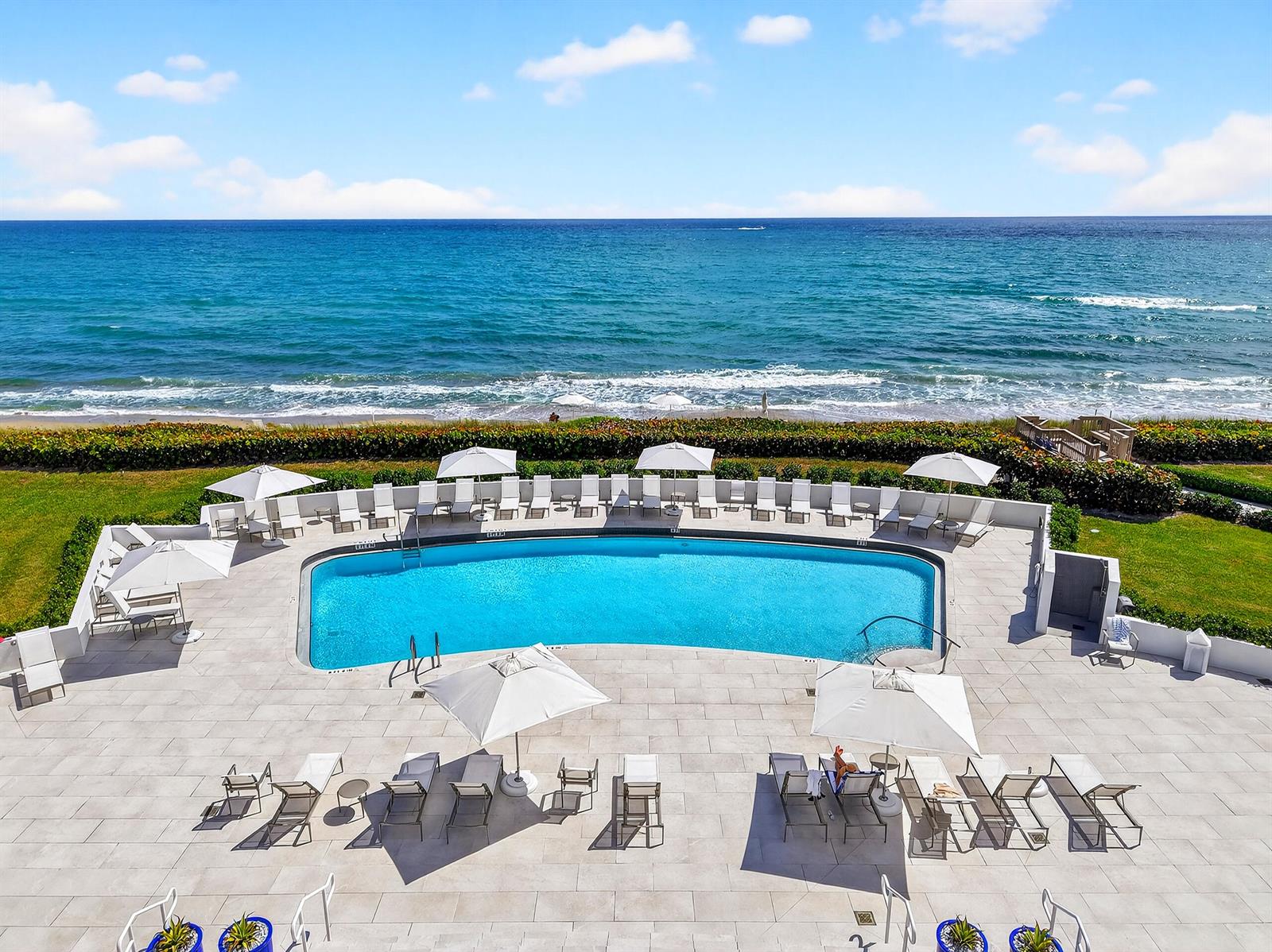 An elevated view of an outdoor swimming pool with lounge chairs and umbrellas by the ocean — 3400 S Ocean Boulevard # I, Palm Beach FL 33480, PALM BEACH, FL