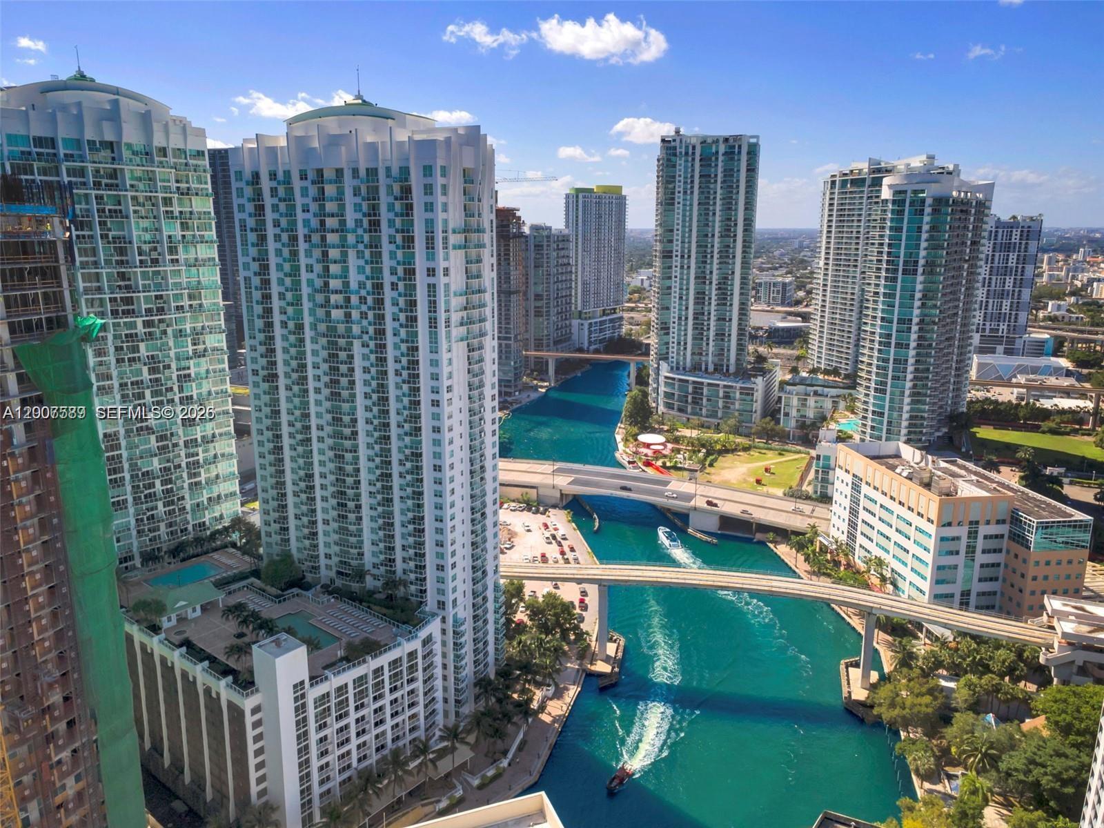 An aerial view shows high-rise apartment buildings along a canal in a city — 31 SE 5th St # 3002, Miami FL 33131, MIAMI, FL