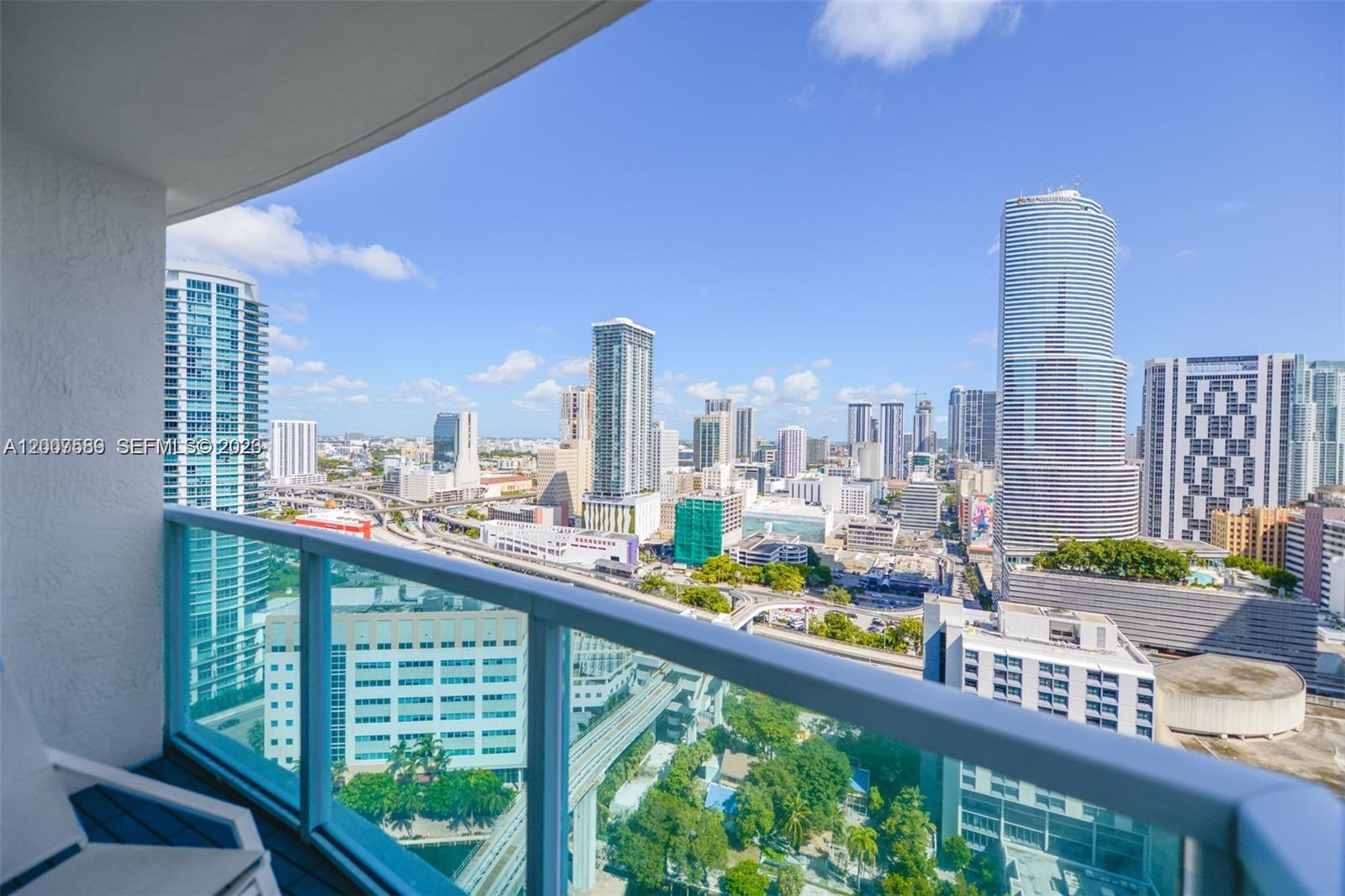 A high-rise balcony overlooks a dense urban cityscape with multiple skyscrapers and highway infrastructure — 31 SE 5th St # 3002, Miami FL 33131, MIAMI, FL