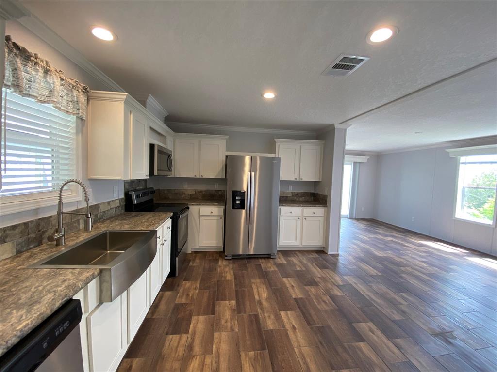 A kitchen with white cabinets, stainless steel appliances, and wood-look tile flooring — 538 FLEETWOOD STREET, NORTH PORT, FL